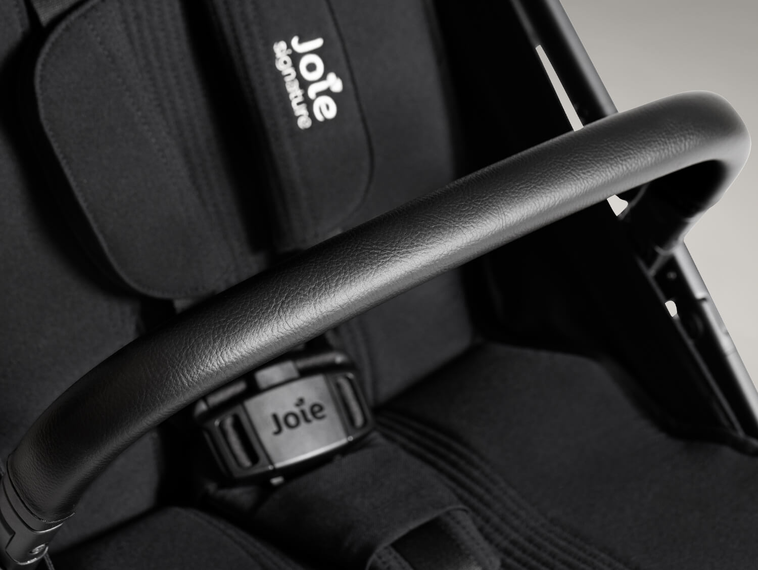 Premium black vegan leather arm bar shown over the plush softgoods on the parcel pop travel stroller.
