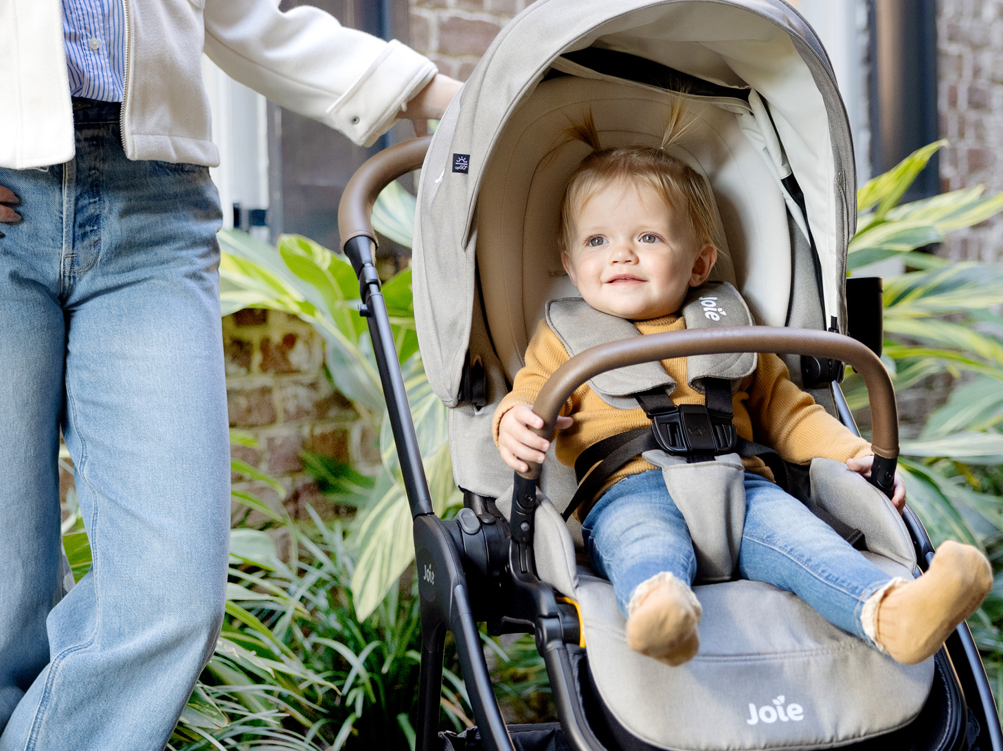 Happy child sitting securely in Kava stroller in dove outside
