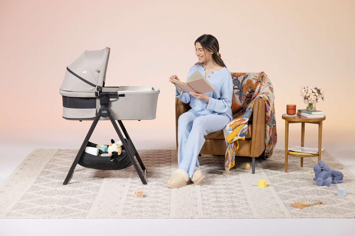 mother reading to infant in carry cot
