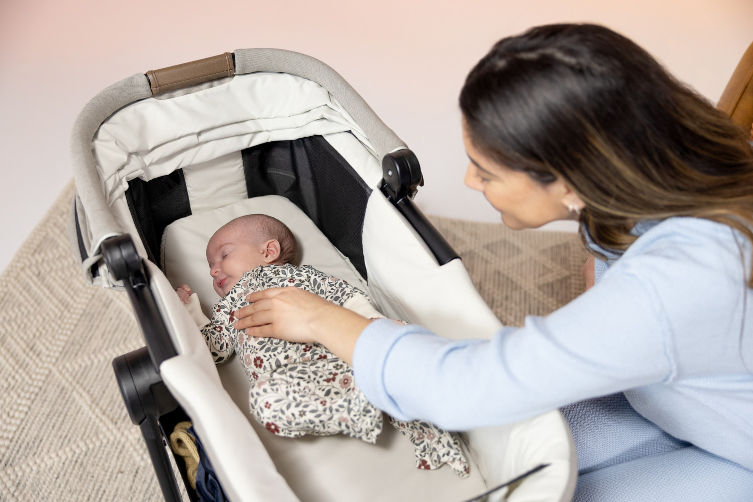 mother looking into carry cot with infant in it 