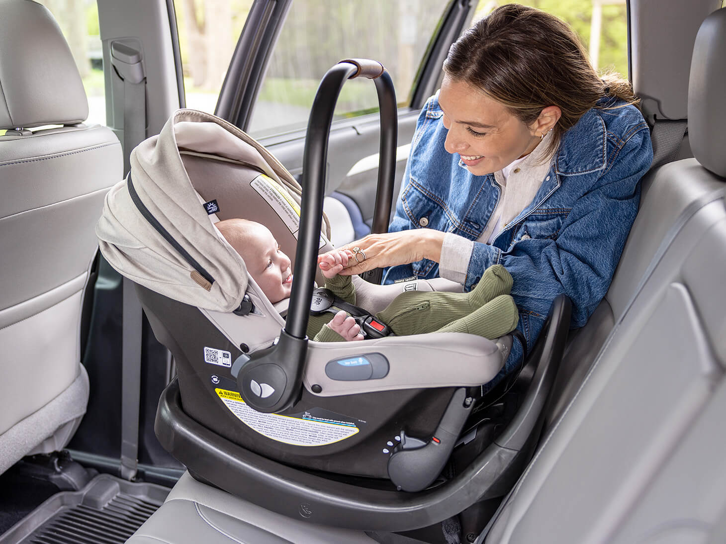 Mom with baby buckled in mint latch infant car seat secured on Base AR infant car seat base in black in car
