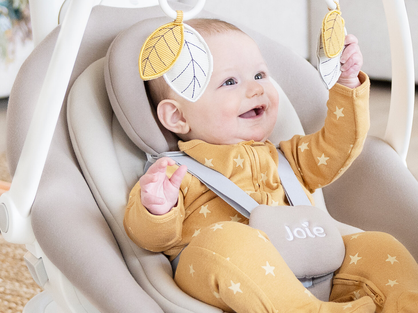 baby secured in ancho wind-up swing and rocker playing with 2 soft toys
