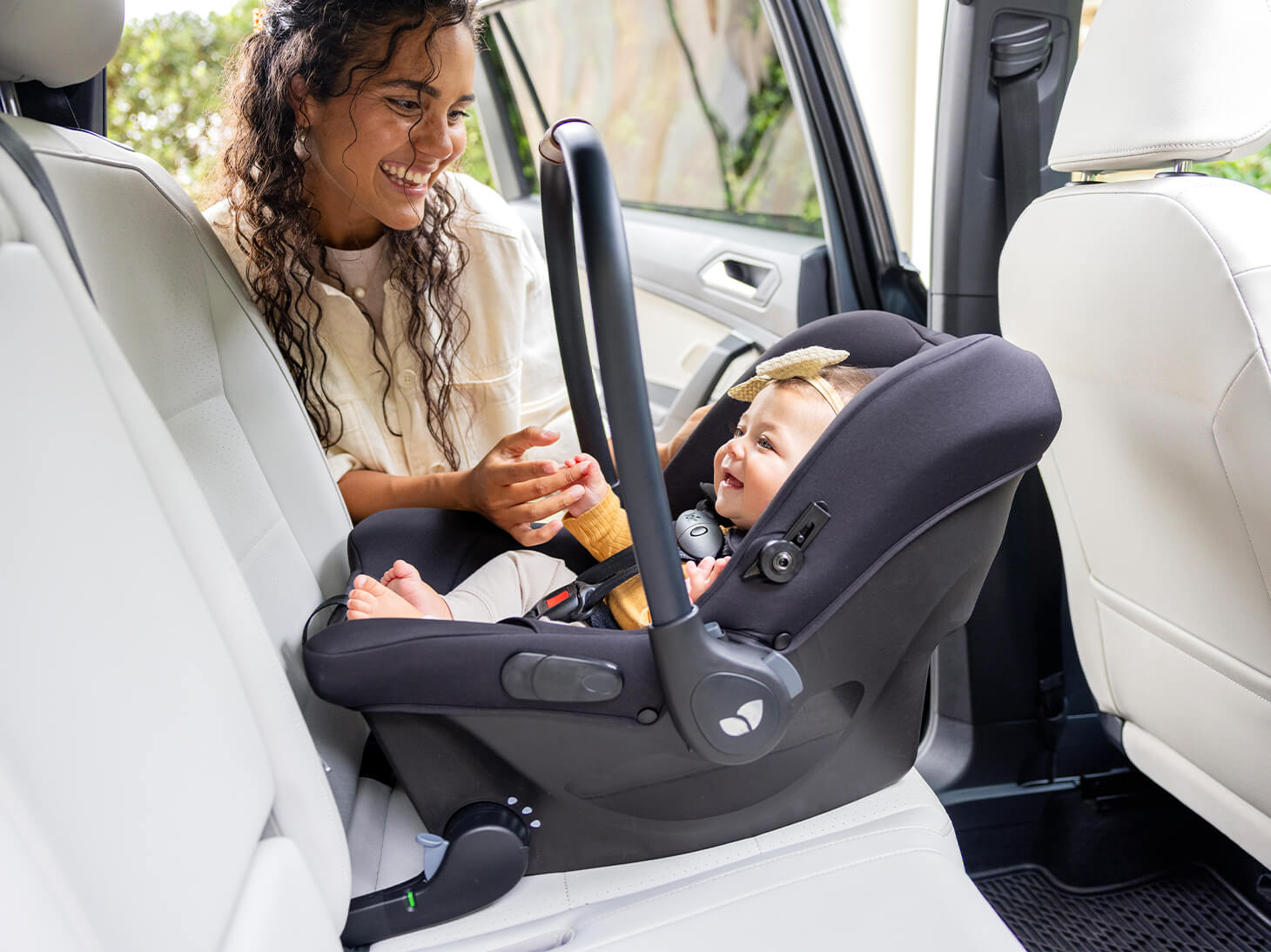 Mom smiling at baby secured in mint latch car seat secured in backseat of car