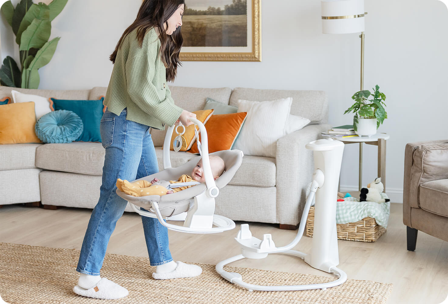 Maman dans son salon soulevant la balancelle Joie whimsy de sa base et la portant en mode transat nomade
