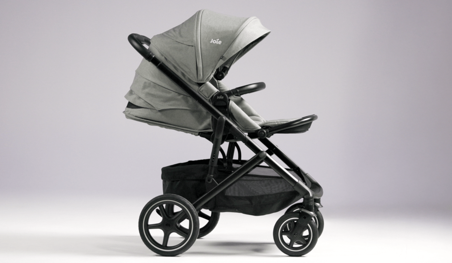 joie elara pram in gray fashion fully reclined facing right in front of a purple wall