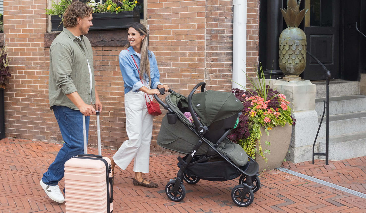 mum and dad outside a hotel with mum pushing joie mydrift stroller with baby in it while dad pushes a stroller