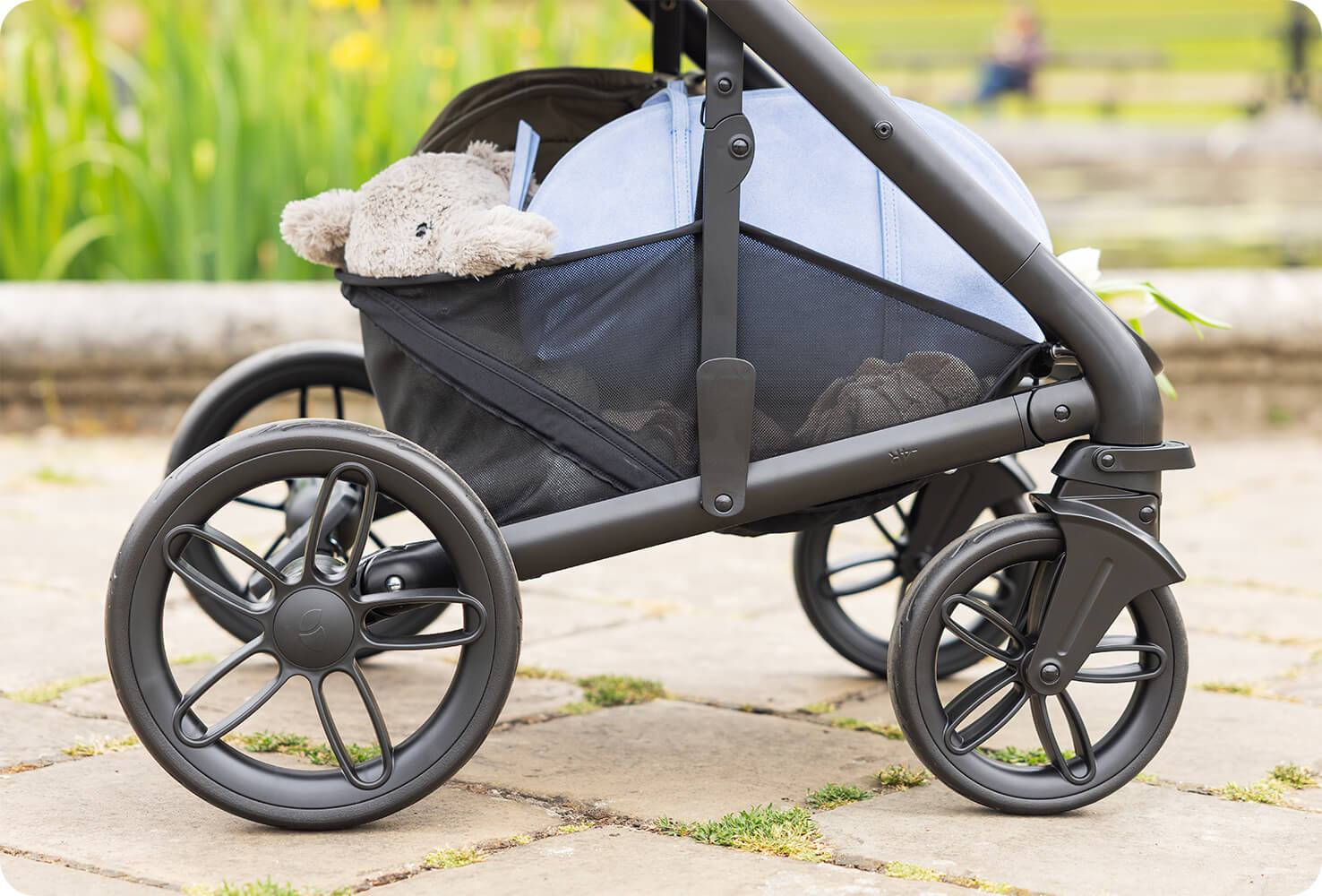 Close up of the large storage basket full of items in the Joie chrome 2 pram