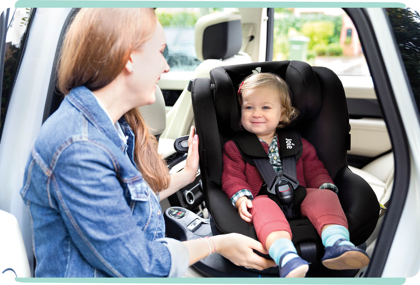 Mom spinning toddler daughter to rearfacing position in a black I-Spin 360 car seat.