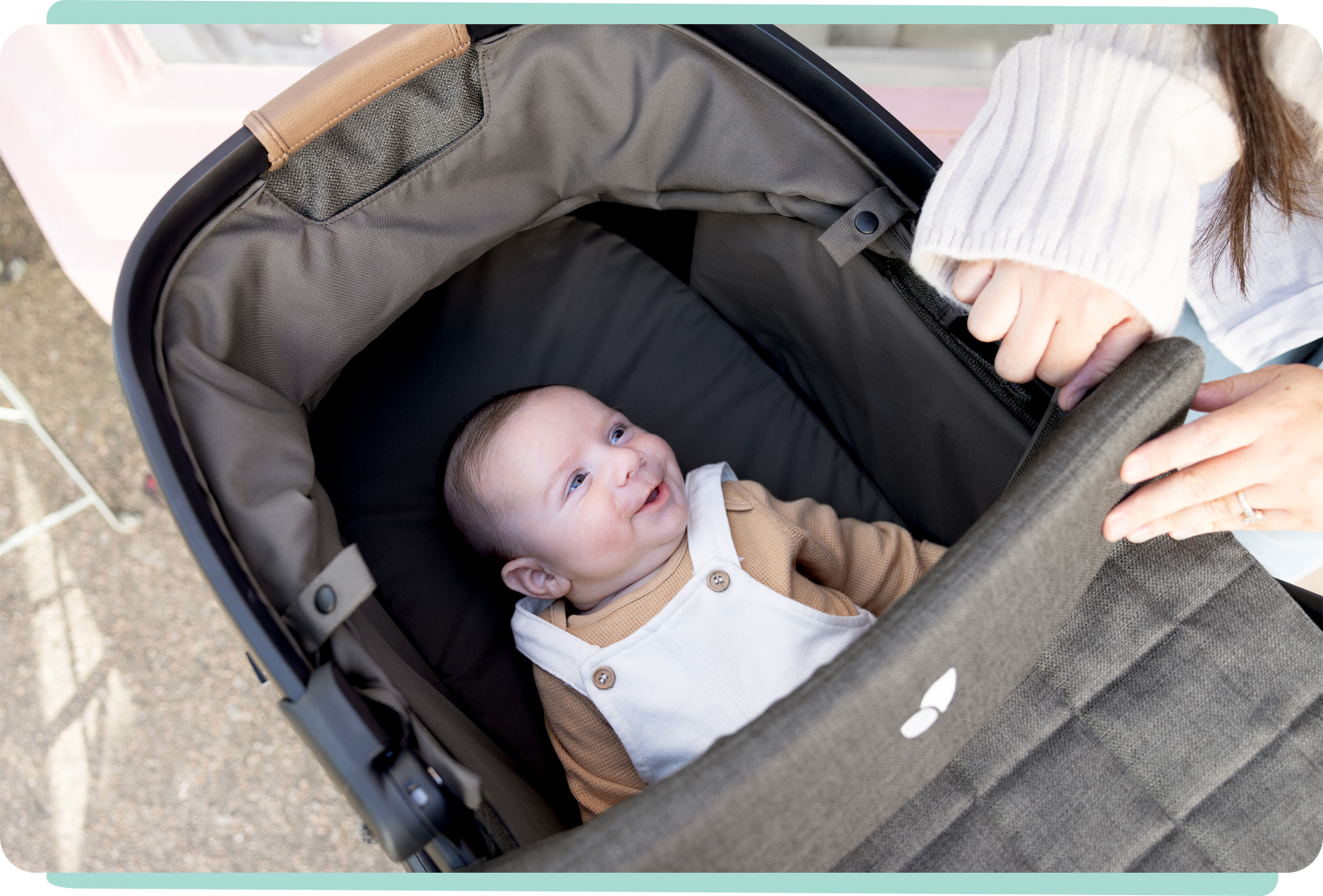Smiling baby looking at mum while laying in gray honour carry cot