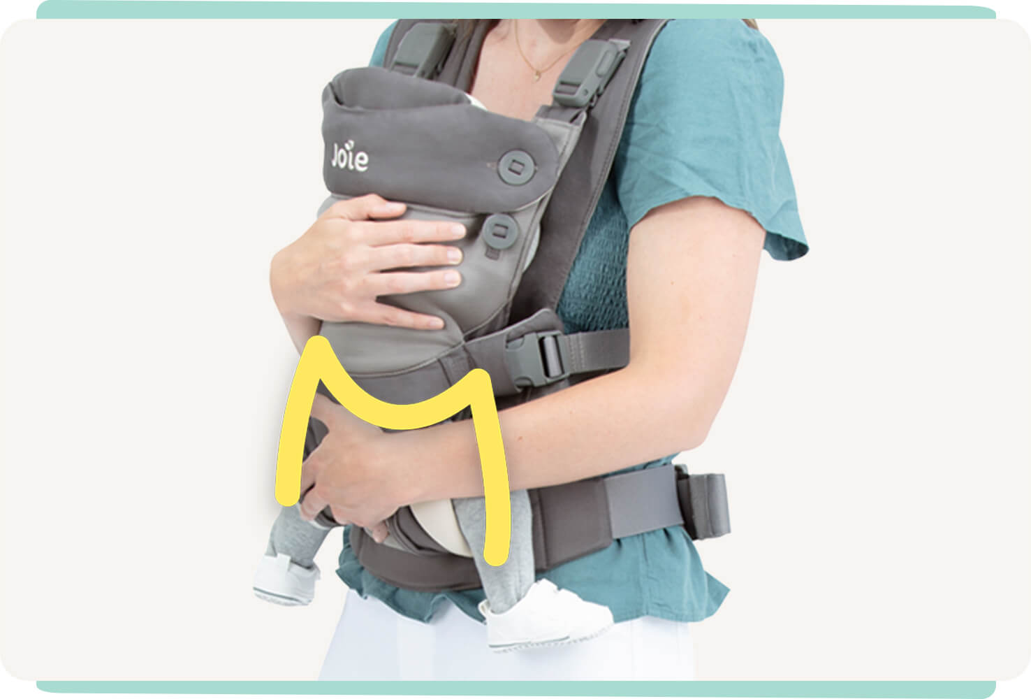 Gros plan sur un bébé installé dans un porte-bébé 3-en-1 Joie Savvy Lite, coloris gris, avec une ligne jaune indiquant la forme en « M » des hanches du bébé.