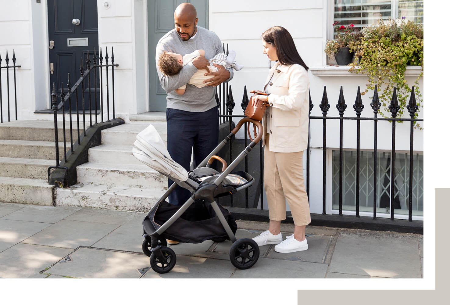 Joie finiti-Kinderwagen in Hellgrau in Liegeposition mit Mama und Papa, während der Vater das Baby in den Kinderwagen legt.
