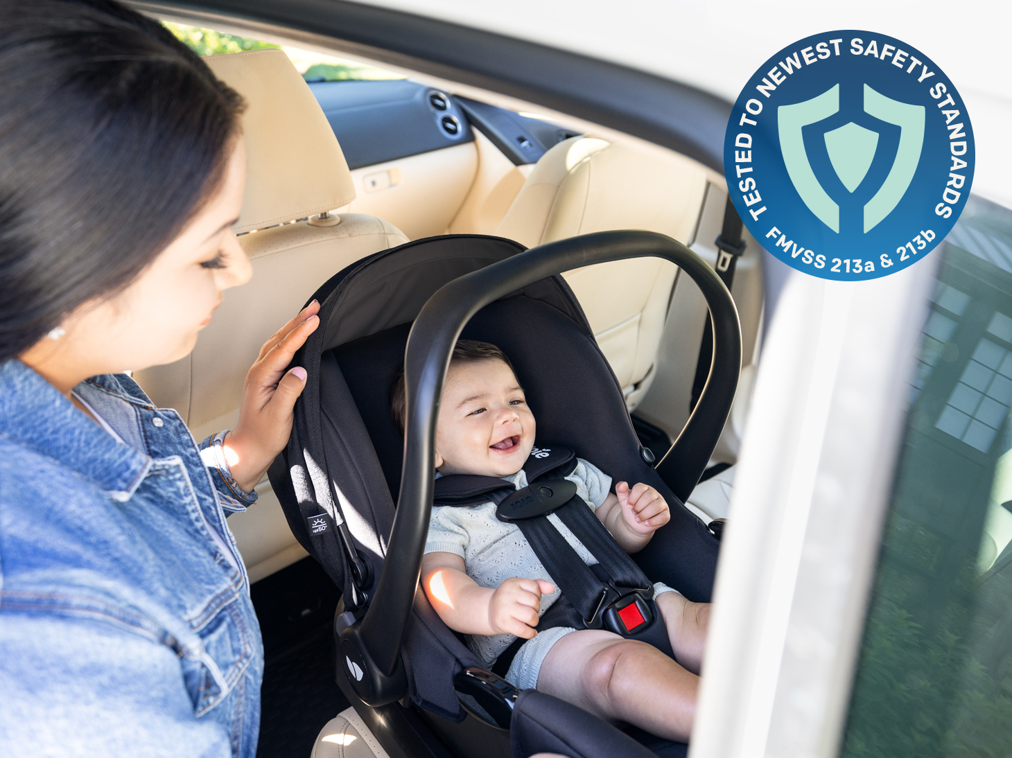 Baby in rue infant car seat and base in car with FMVSS 213a FMVSS 213b logo. 
