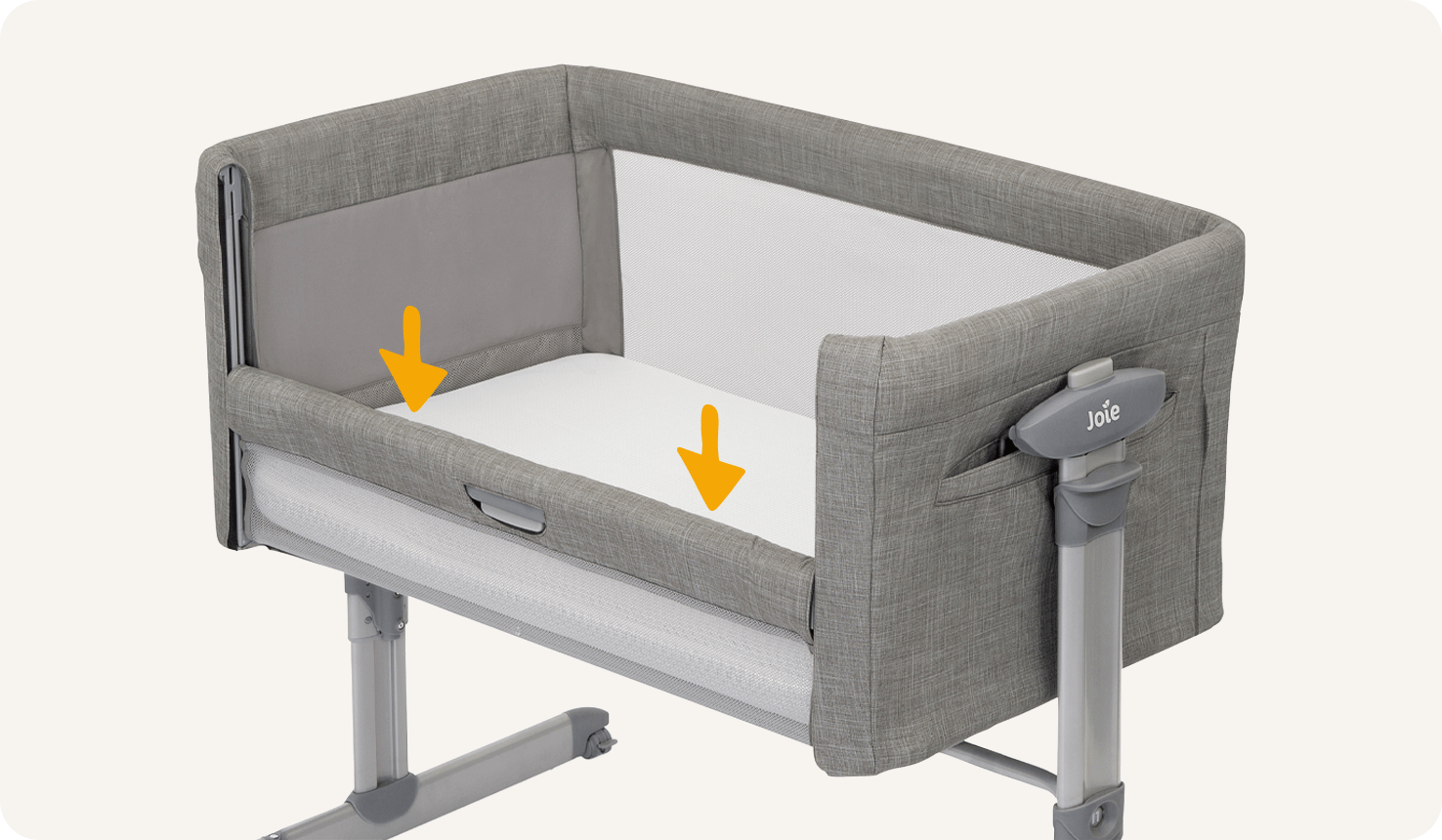 Right angle zoomed in view of light grey Joie roomie glide bedside crib with lift and lower side panel down. Two downward orange arrows display this feature.