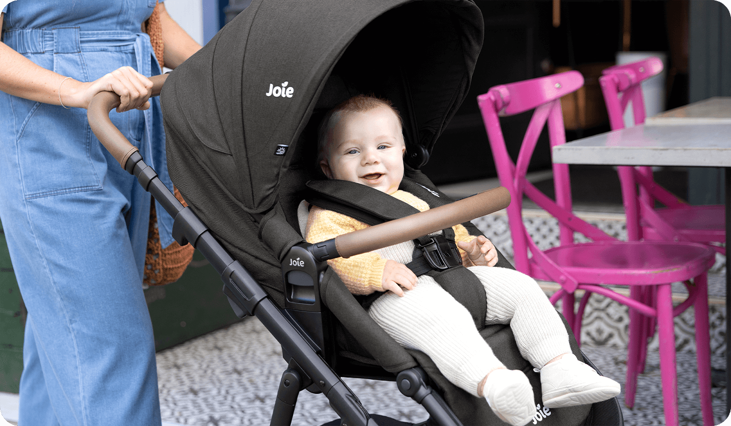 Ein glückliches Baby in Joie alore Kombi-Kinderwagen