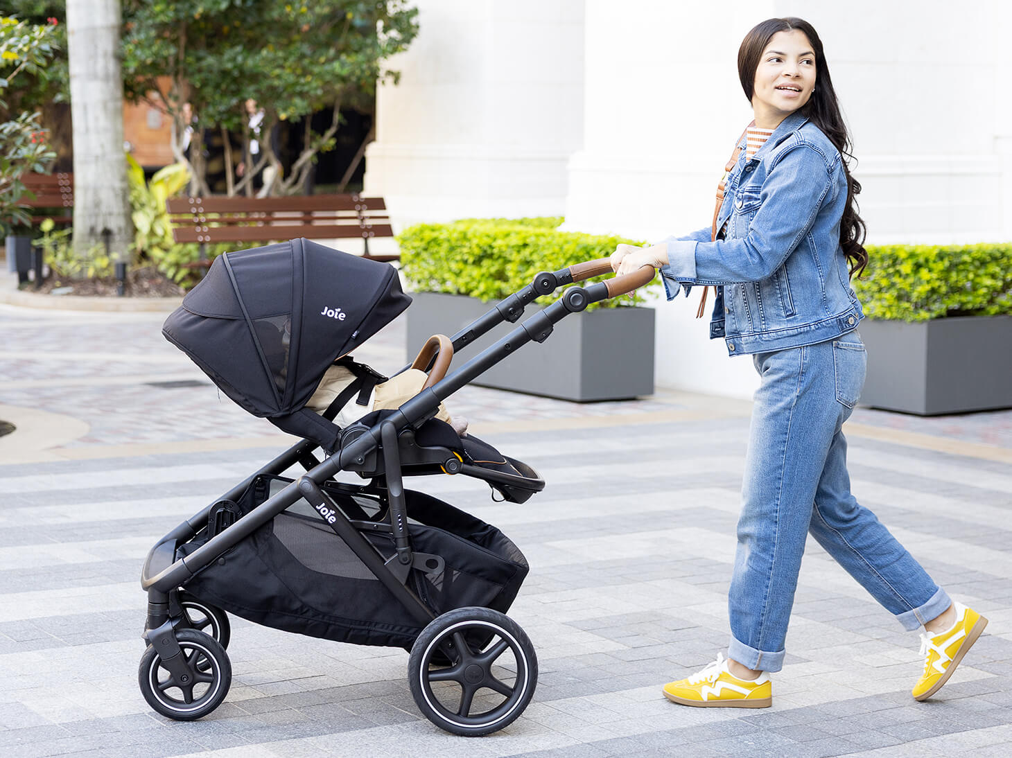 Mom pushing baby in chive stroller in shale with extended canopy
