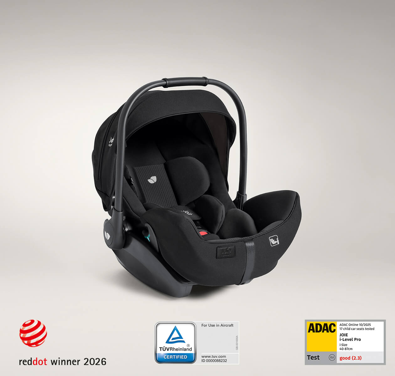 Joie Signature i-Level Pro deep reclining i-Size baby car seat from a right angle with TUV airplane-certified label, ADAC test award label, and Red Dot design award label.