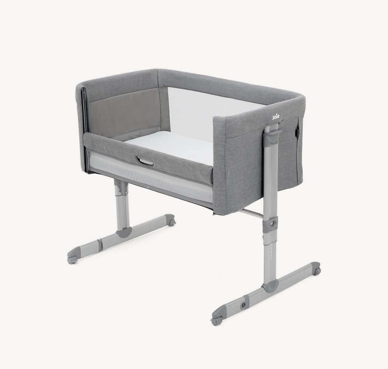  Light gray Joie roomie bedside crib at a right angle, with lift and lower side panel down.