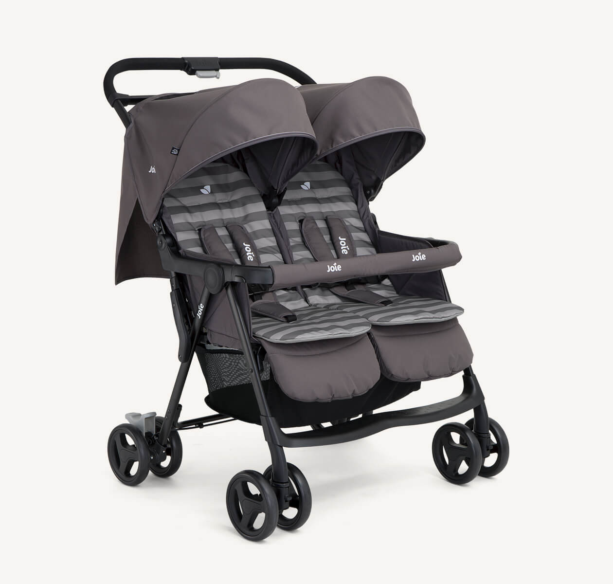  The Joie Aire Twin side-by-side double stroller in light gray at an angle, with a peach coloured seat insert on the left seat and a light blue insert on the right seat.