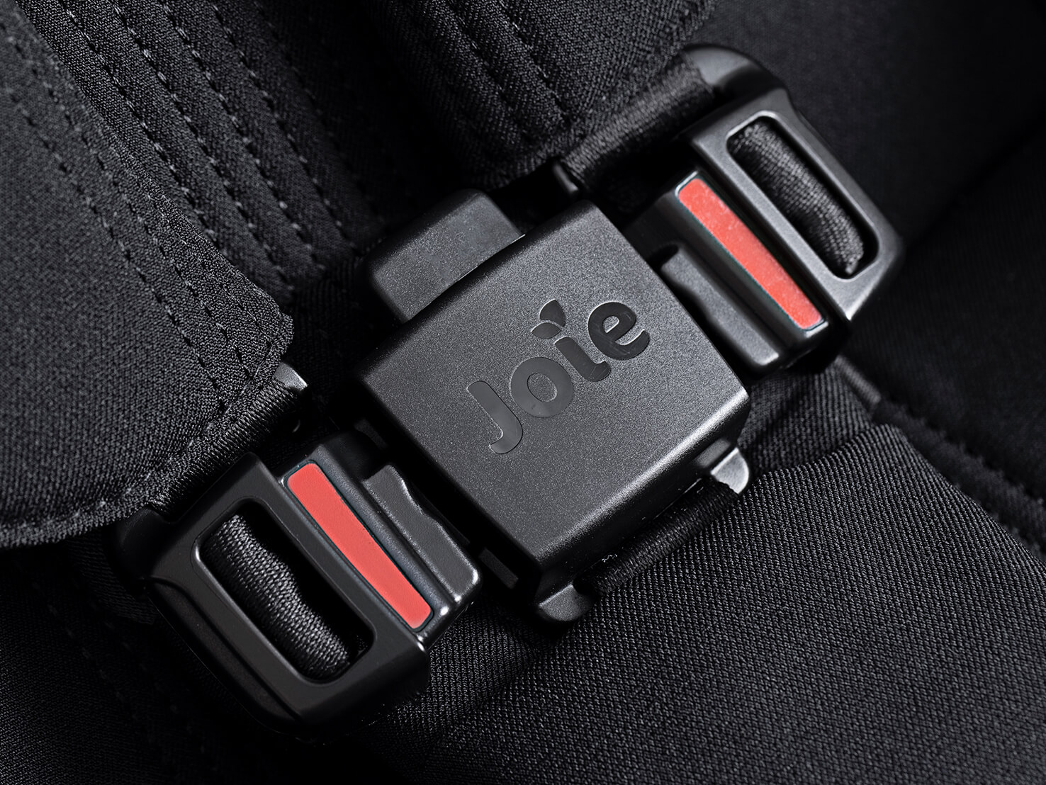 A close up of the Joie Signature versiti pushchair in black buckle shows the magnetic buckles.