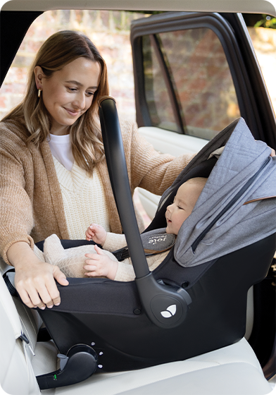 Baby in Sprint infant carrier being installed into back seat of car by happy mother