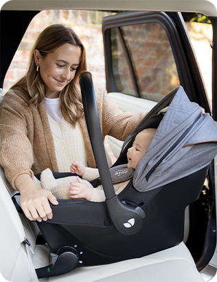 Bambino nel seggiolino Sprint installato sul sedile posteriore dell'auto da una madre felice