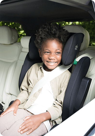 Enfant assis dans un rehausseur à dossier haut i-Traver noir de Joie, attaché en toute sécurité dans la voiture.