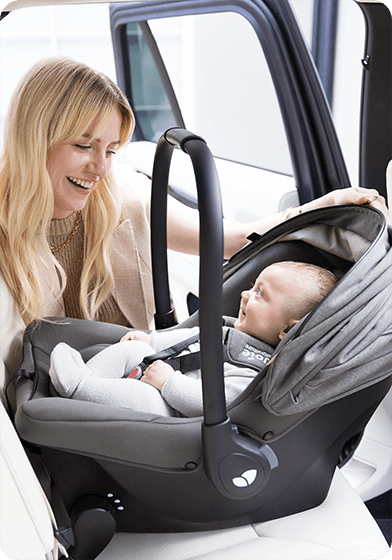 Maman souriante face à son bébé installé dans le siège auto sprint™ de Joie.