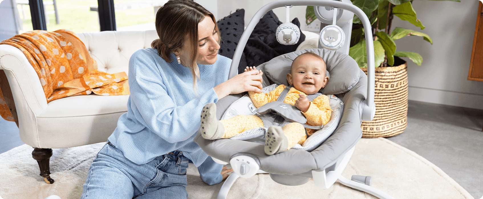 Mum sitting on the floor next to baby in the Joie Serina 2in1 baby swing