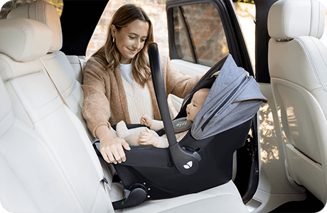 Baby in Sprint infant carrier being installed into back seat of car by happy mother