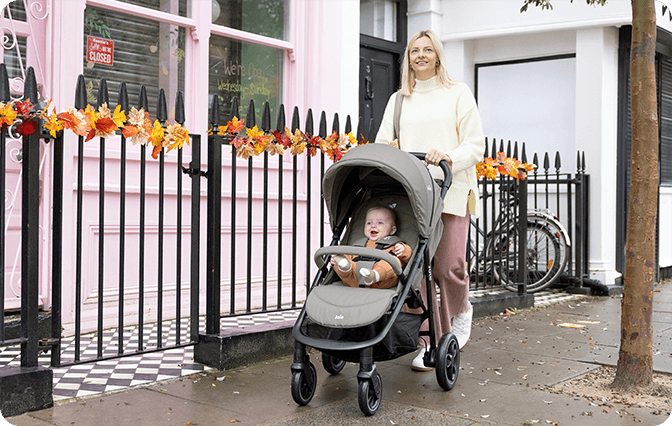 Parent pushing Joie Litetrax pushchair in gray with happy baby on city walk.
