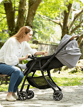 Image of a mother sitting down and looking at baby in a stroller.
