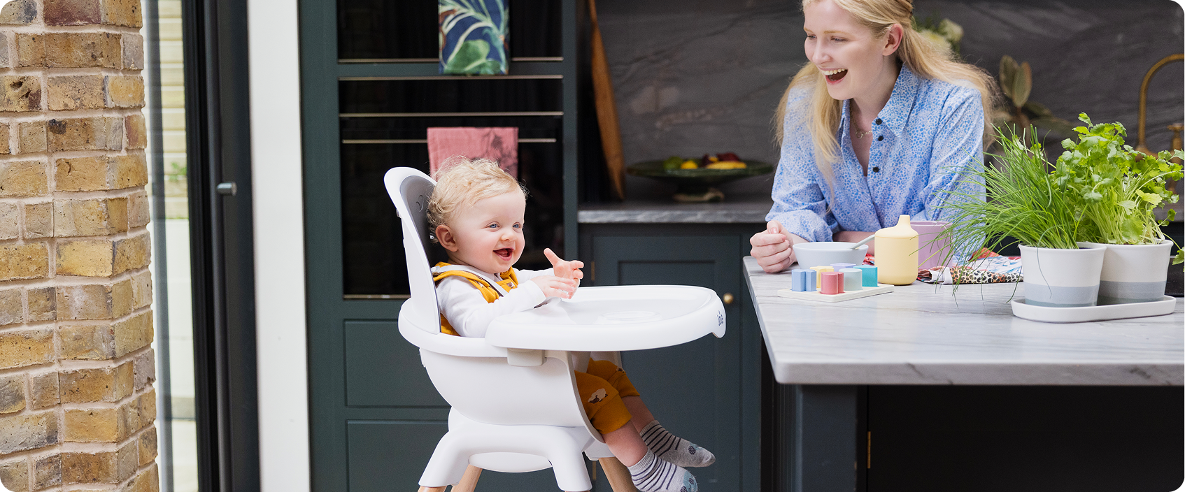 Mum sitting on the floor next to baby in the Joie Serina 2in1 baby swing