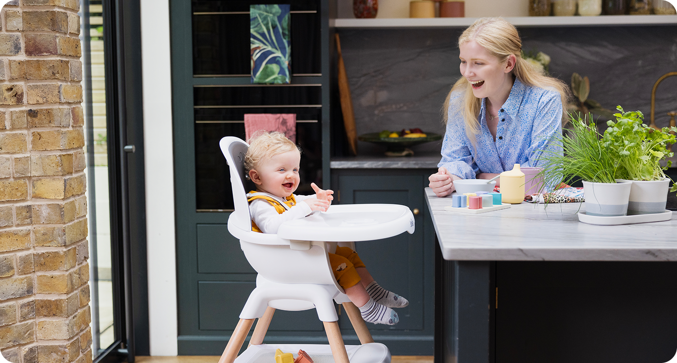 Mum sitting on the floor next to baby in the Joie Serina 2in1 baby swing