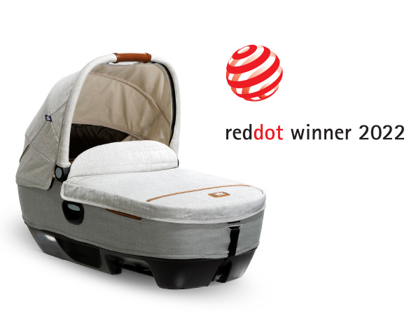 A gray Joie Signature calmi R129 car cot at an angle facing to the right, with the Red Dot Design award logo above and to the right
