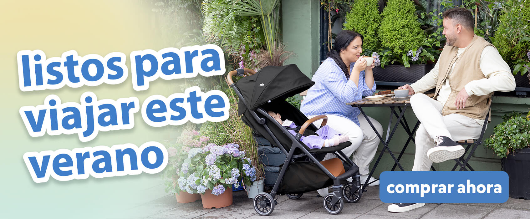 Padres charlando tomando caf&eacute; en una mesa de cafeter&iacute;a en un jard&iacute;n al aire libre. El beb&eacute; est&aacute; relajado c&oacute;modamente a su lado en el cochecito Joie pact pro. El texto en la imagen destaca los imprescindibles para viajar en verano.