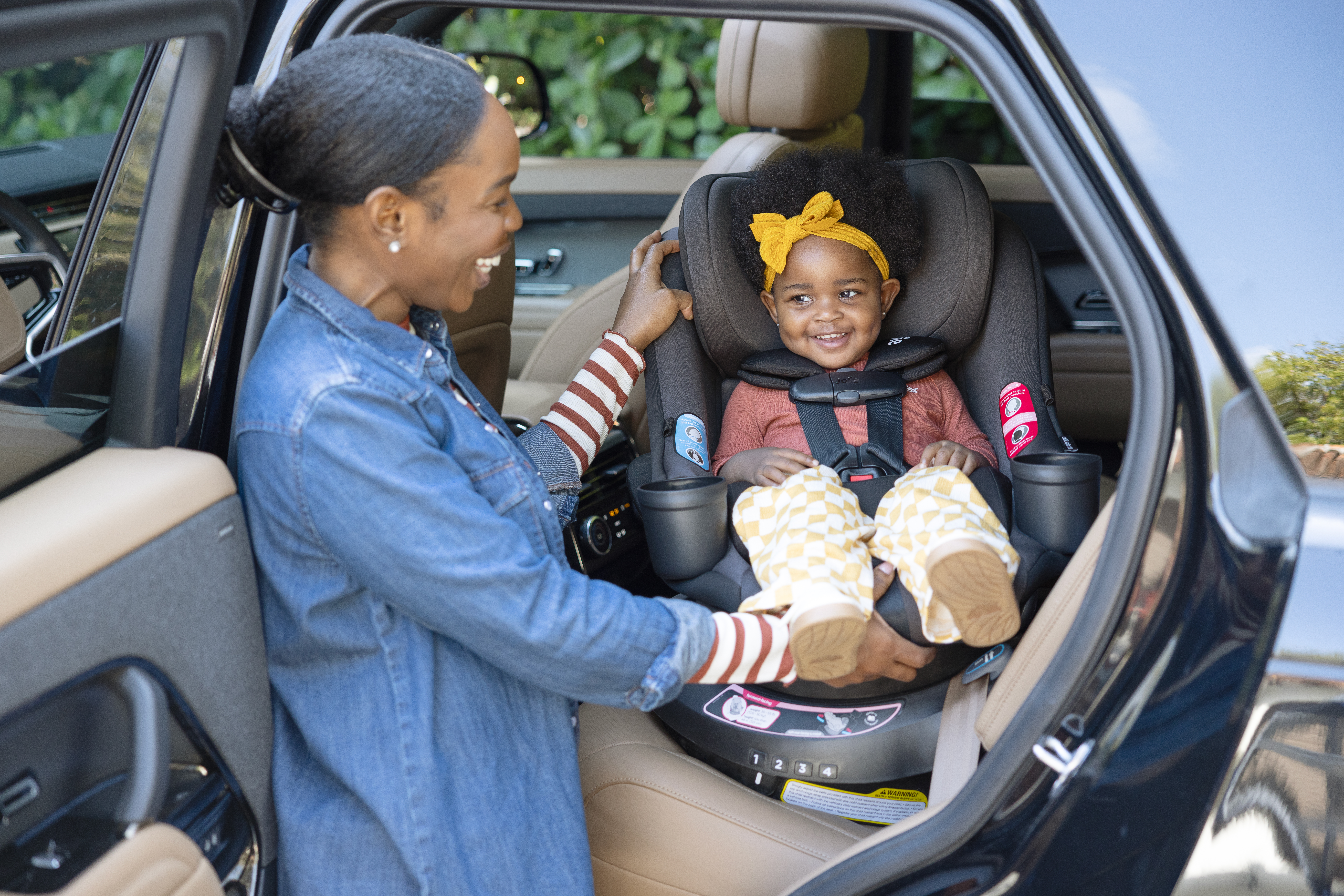image of a toddler in a spinning car seat facing a father in the back seat of a car with the door open. 