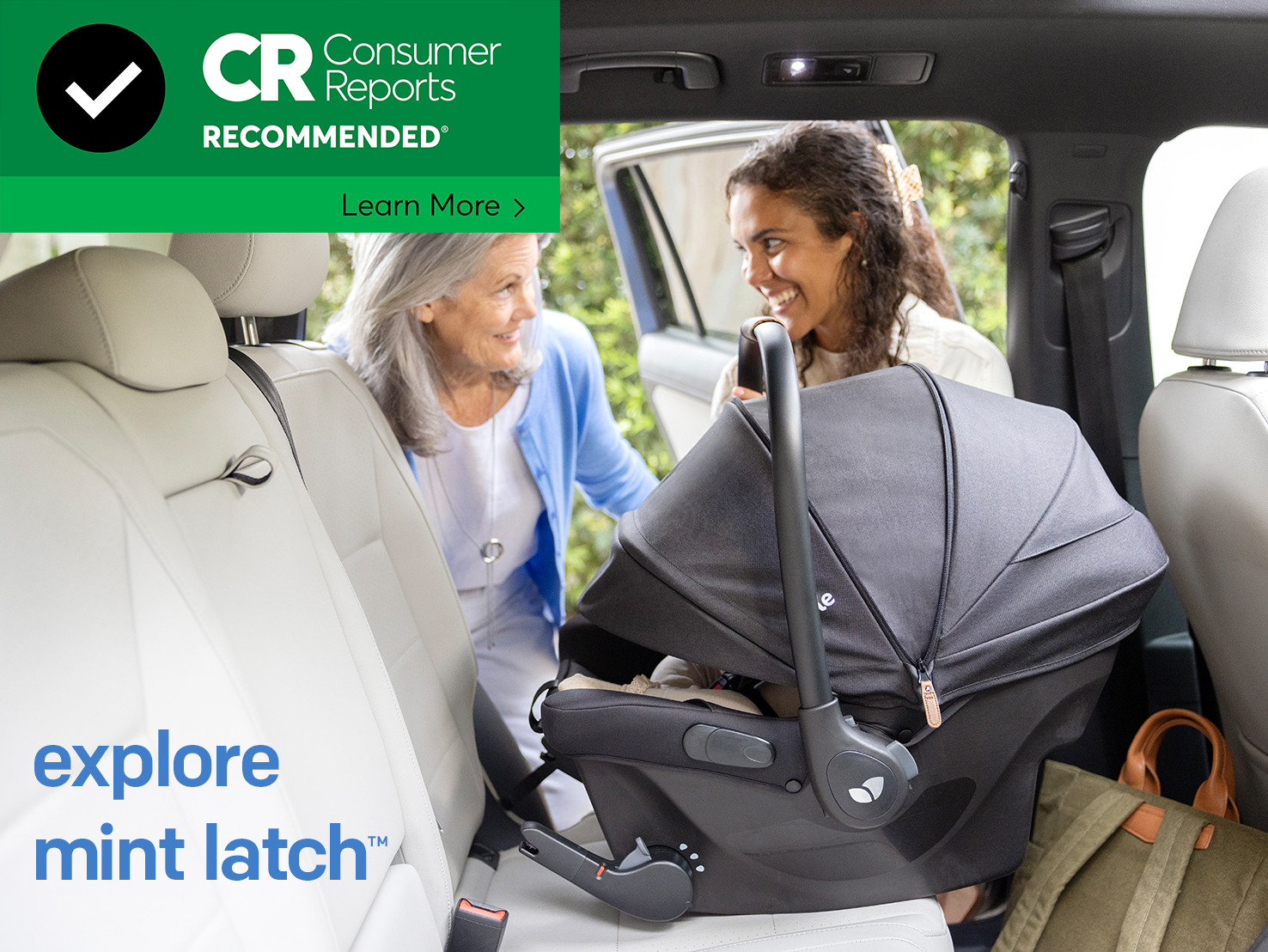 image of a mother smiling at a baby in a car seat installed in the back seat of a car with light interior. 