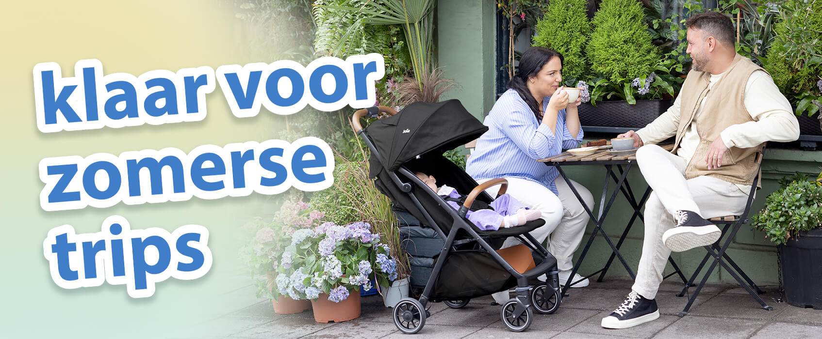 Ouders zitten te kletsen met een kop koffie aan een caf&eacute;tafel in een tuinsetting buiten. De baby ligt er comfortabel naast in de Joie pact pro kinderwagen. Tekst op de afbeelding benadrukt de must-haves voor zomerse uitstapjes.